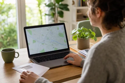 Symbolbild zum Ratgeber „Grundversorger finden: Postleitzahl reicht nicht“: eine Person sucht am Laptop die Adresse, ein Briefumschlag liegt daneben.
