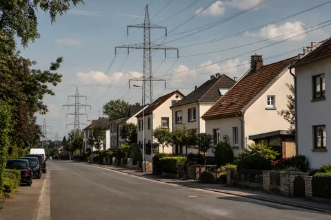 Symbolbild zum Ratgeber „Warum die Grundversorgung fast immer mehr kostet“: eine ruhige Wohnstraße mit Stromleitungen bei Tageslicht.